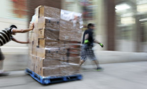 Warehouse workers pushing a pallet of boxes
